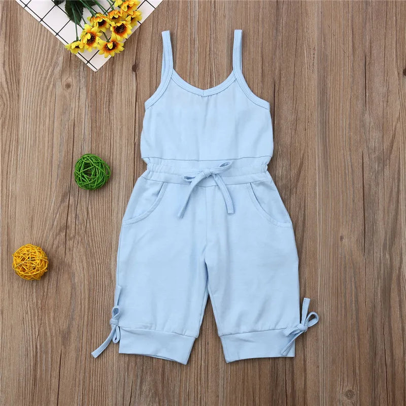 Light blue romper with straps on a wooden surface with decorative elements.