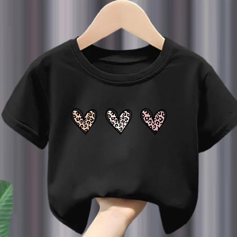 Black t-shirt with leopard print hearts on a hanger against a gray curtain background