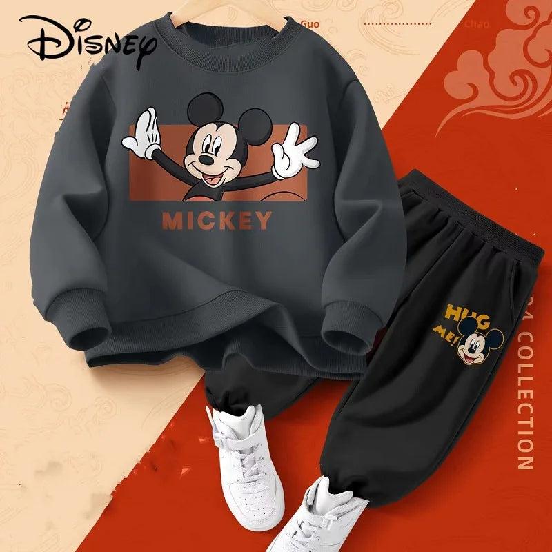 Black sweatshirt with Mickey Mouse design and black pants on a red and beige background, featuring Disney branding.