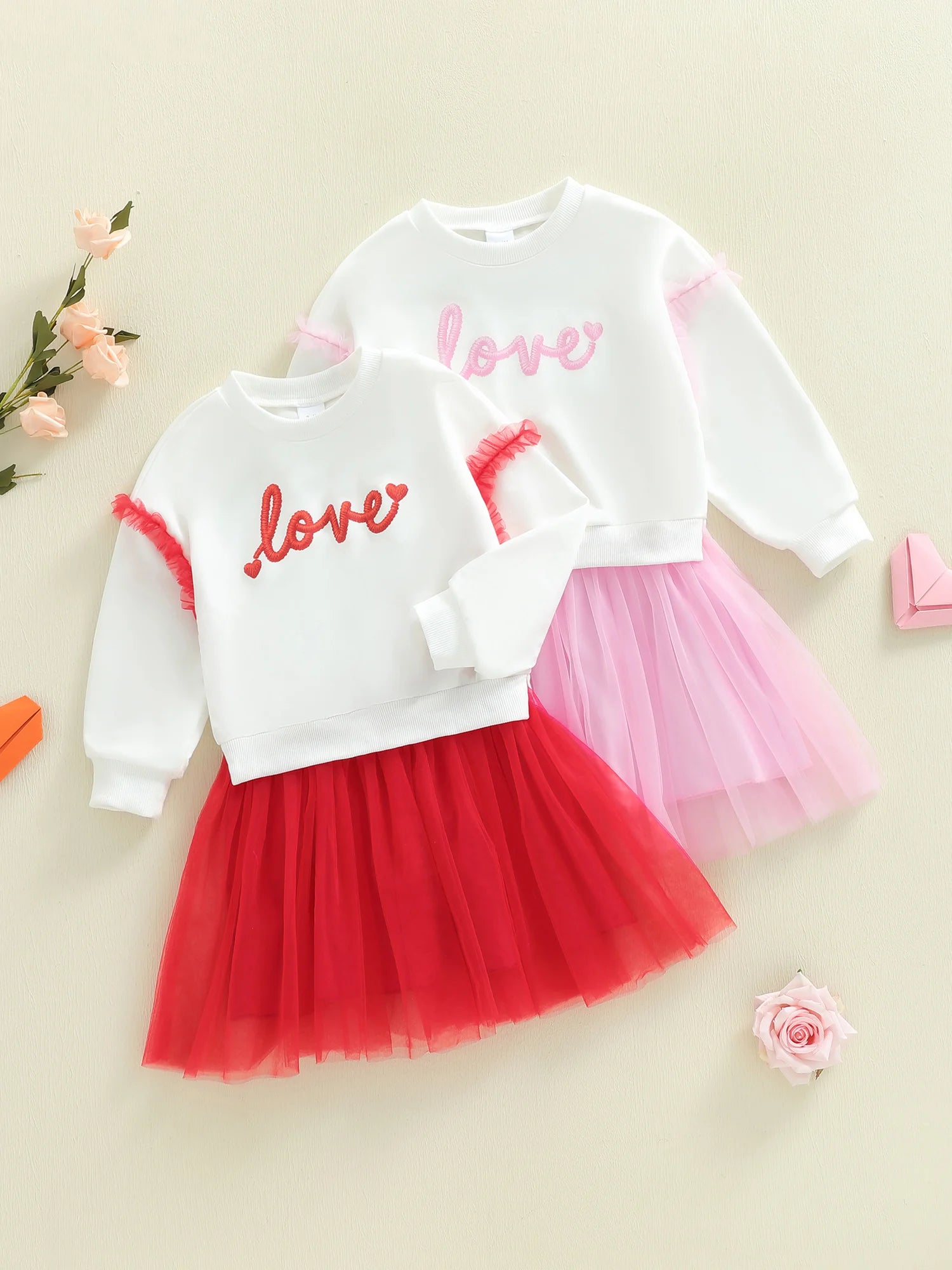 Children's outfit with white top and red and pink tutu skirt on a beige background