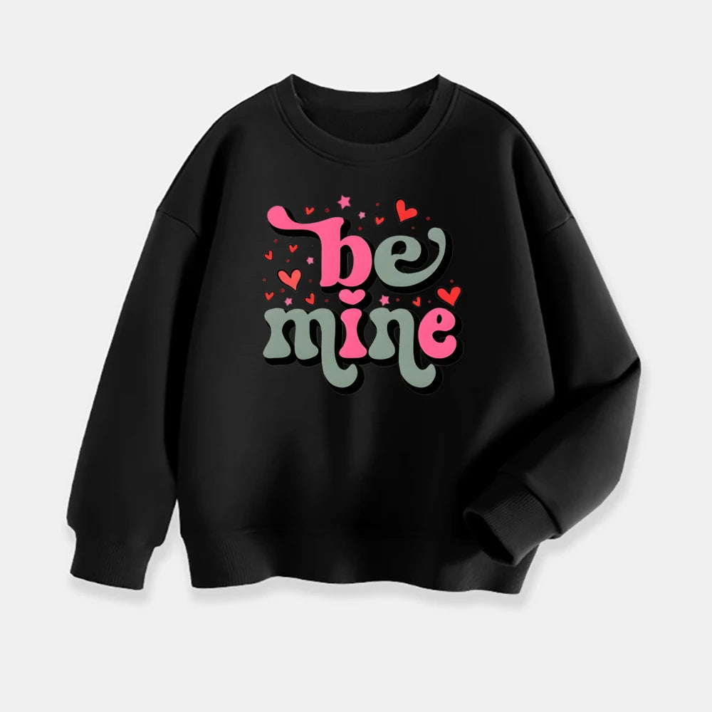 Black sweatshirt with 'be mine' text in pink and green on a light gray background