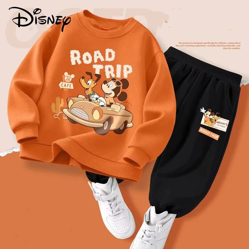 Orange sweatshirt with cartoon design and black pants on a brown background, featuring Disney branding.