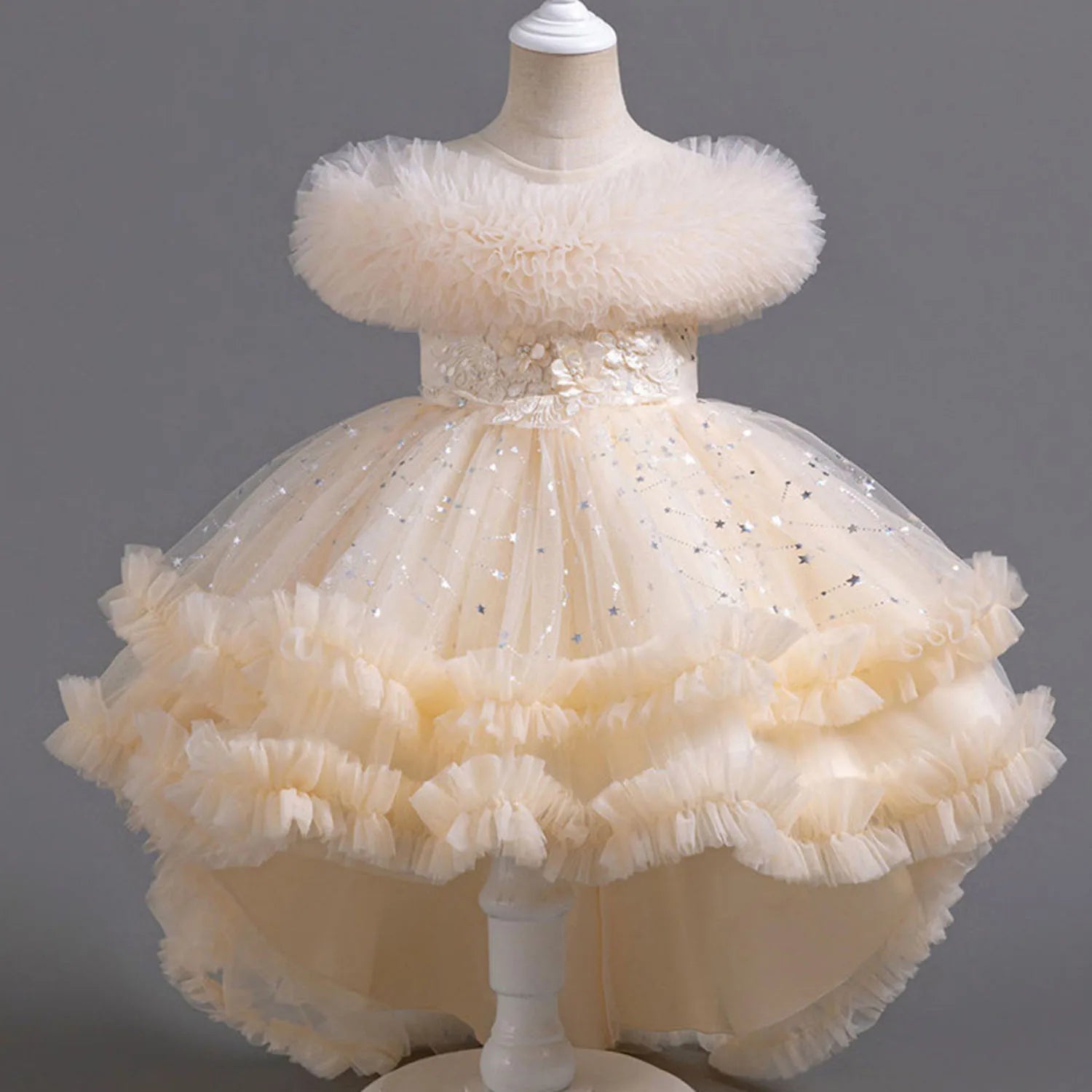 Beige ruffled dress on a mannequin against a gray background