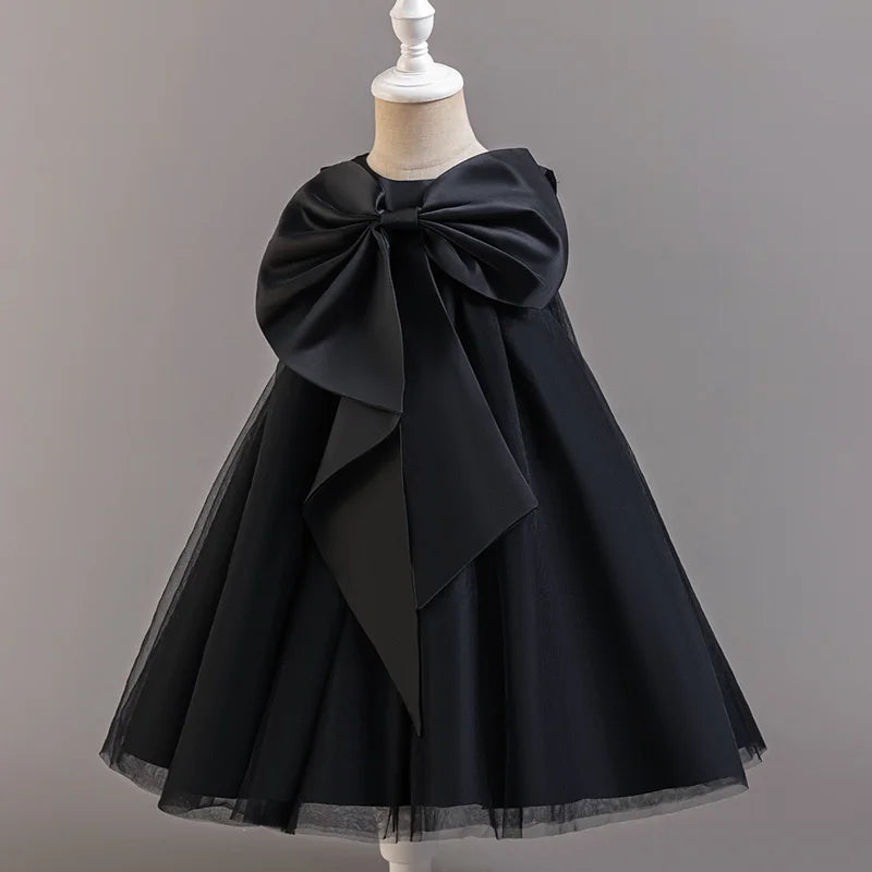 Black dress with a large bow on a mannequin against a gray background